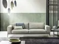 Modernes Wohnzimmer mit hellem Sofa, grüner Wand und stilvollem farbkonzept. Hängende Lampen und dekorative Vasen ergänzen das Ambiente.