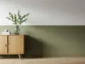 Ein Flur, halbhoch gestrichen in einem beruhigenden Grünton. Ein schlichtes Sideboard aus Holz mit Deko-Elementen.