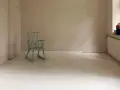 Ein hell gestrichener holzboden mit einer mintgrünen Schaukelstuhl.