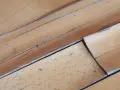 Wasserflecken auf Holzboden, die das helle Holz verfärben und die Maserung hervorheben.