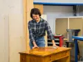Frau schleift Holzmöbel, um alte Farbe zu entfernen.