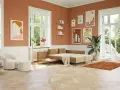 Ein Wohnzimmer mit orangefarbenen Wänden und einem beigen Sofa. Welche Farbe passt zu Orange? Hier: Beige, Weiß und Grün.