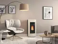 Gemütliches Wohnzimmer mit modernem Pellet-Kaminofen. Die warme wandfarbe hinter kaminofen harmoniert mit dem cremefarbenen Ofen und dem bequemen Sessel.