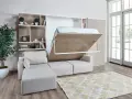 Ein verstecktes Bett im Wohnzimmer wird aus einem Schrank herausgeklappt. Daneben ein Sofa und ein Bücherregal.