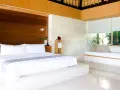 Luxuriöses Schlafzimmer mit einem großen weißen Bett, das den Unterschied zwischen einem King und Queen Bett verdeutlicht. Holzakzente und viel Licht.
