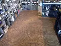 Ein Weinladen mit Regalen voller Flaschen und einem Boden aus Hirnholz, das wie ein Mosaik aus Holzscheiben verlegt ist.