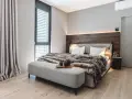 Gemütliches Schlafzimmer mit Holzbettkopfteil, flauschiger Decke und Sitzbank. Tolle zimmer inspo für ein modernes Ambiente.