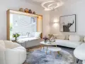 Modernes Wohnzimmer mit weißem Sofa, gemütlichem Sessel und einem Fensterplatz. Die schale dekorieren modern mit Vasen und Büchern.