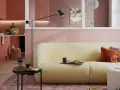 Ein hellgelbes Sofa mit orangefarbenen und lila Kissen vor einer rosafarbenen Wand. Die Frage, welche Farbe passt zu rosa, wird hier stilvoll beantwortet.