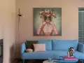 Ein blauer Sofa mit Kissen vor einer Wand mit einem surrealen Gemälde, das eine Frau mit Blumen und Schmetterlingen auf dem Kopf zeigt. Eine kreative Wandgestaltung, die zum Träumen einlädt.