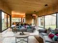 Gemütliches Wohnzimmer mit holzverkleideten Wänden und Decke, das zeigt, wie man eine holzdecke modern gestalten kann. Große Fensterfronten bieten Blick ins Grüne.