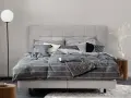 Stilvolle Schlafzimmer Ideen mit einem grauen Boxspringbett, gestreifter Bettwäsche und modernen Akzenten.