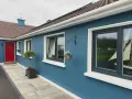 Ein blaues Haus mit roten Tür und dunklen Kunststofffenstern. Die Fensterrahmen sind in einem eleganten Anthrazit gehalten, was die modernen Kunststofffenster Farben unterstreicht.