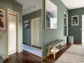 Grüne Wand im Flur mit moderner Kunst und Spiegel. Tolle Flur Wand Ideen für ein stilvolles Zuhause.