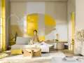 Eine Frau sitzt auf einem Sofa in einem hellen Wohnzimmer. Die Wand hinter ihr ist mit geometrischen Formen in Gelb, Beige und Grau gestaltet. Die Frage, welche Farbe passt zu Gelb, wird hier mit warmen Erdtönen und neutralen Farben beantwortet.