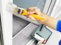 Mit welcher Farbe kann man Kunststoff streichen? Ein Pinsel mit weißer Farbe wird auf einen weißen Kunststoffrahmen aufgetragen.