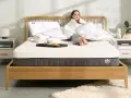 Frau genießt Frühstück im Bett. Die Frage, wie lange Matratze liegen lassen, ist hier nebensächlich, Hauptsache bequem.