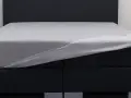 Ein graues Spannbettlaken wird über ein Boxspringbett gezogen. So beziehe ich ein Boxspringbett – einfach und schnell.