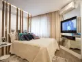 Ein modernes Schlafzimmer mit einem eleganten Bett, vielen Kissen und einem versteckten TV im Spiegel-Schrank.