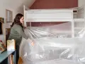 Frau bereitet eine Matratze vor, um sie zu vakuumieren. Sie zieht die Plastikfolie über das Bett.