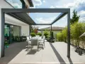 Moderne Terrassenbeschattung Ideen: Ein Essbereich unter einer Pergola mit Glasdach, umgeben von Bambus und Blumen.
