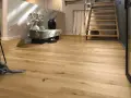 Ein heller Flur mit Treppe und Sitzbank. Der Boden ist aus echtem **Vollholz**, das Wärme und Natürlichkeit ausstrahlt.