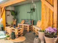 Gemütliche Sitzecke im Hof gestalten mit Palettenmöbeln, bunten Kissen und Lichterkette. Einladend und stilvoll.