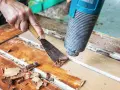 Farbe von Holz entfernen ohne Schleifen: Heißluftföhn und Spachtel lösen alte Lackschichten von einer Holztür.