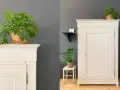 Eine frisch lackierte Kommode in hellem Cremeton, dekoriert mit grünen Pflanzen.