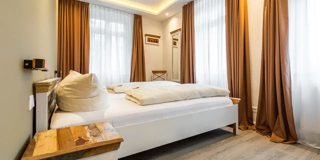 Gemütliches Schlafzimmer mit Doppelbett, Sitzsack und rustikalem Nachttisch. Die Einrichtung der Ferienwohnung ist modern und einladend.
