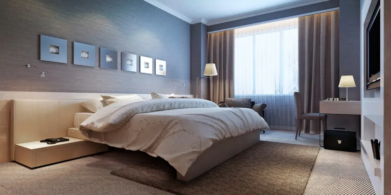 Modernes Schlafzimmer mit einem bequemen Bett, das wie ein wasserbett oder boxspringbett wirkt. Dekorative Wandbilder und ein Schreibtisch mit Lampe.