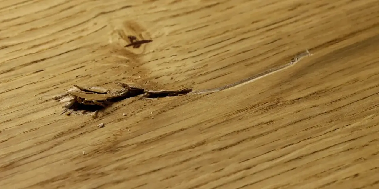 Beschädigter Holzboden mit Rissen und Splittern, bereit zum Ausbessern.