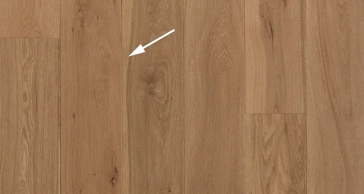 Holzboden mit natürlicher Maserung. Ein weißer Pfeil zeigt auf eine kleine Astloch-Stelle im splint holz.