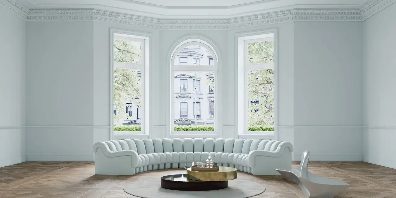 Ein helles Wohnzimmer mit geschwungener Couch, modernem Beistelltisch und einem futuristischen Sessel. Helle Wandfarben schaffen eine luftige Atmosphäre.