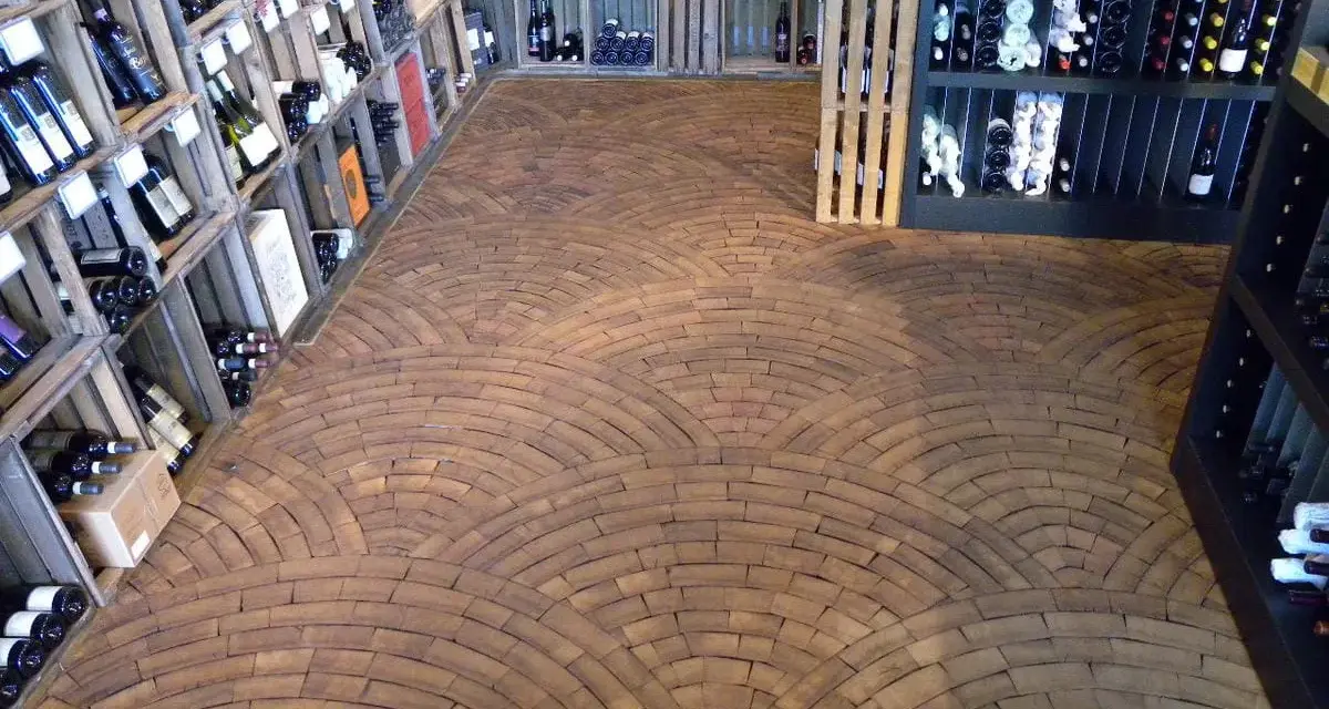 Ein Weinladen mit Regalen voller Flaschen und einem Boden aus Hirnholz, das wie ein Mosaik aus Holzscheiben verlegt ist.