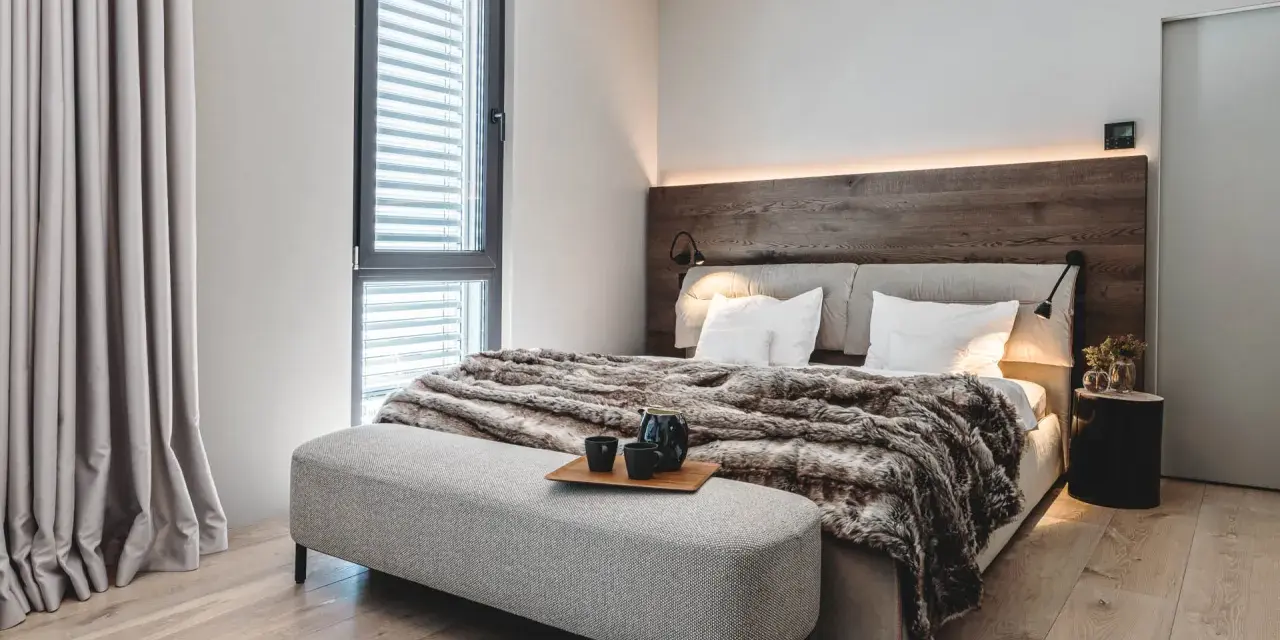 Gemütliches Schlafzimmer mit Holzbettkopfteil, flauschiger Decke und Sitzbank. Tolle zimmer inspo für ein modernes Ambiente.