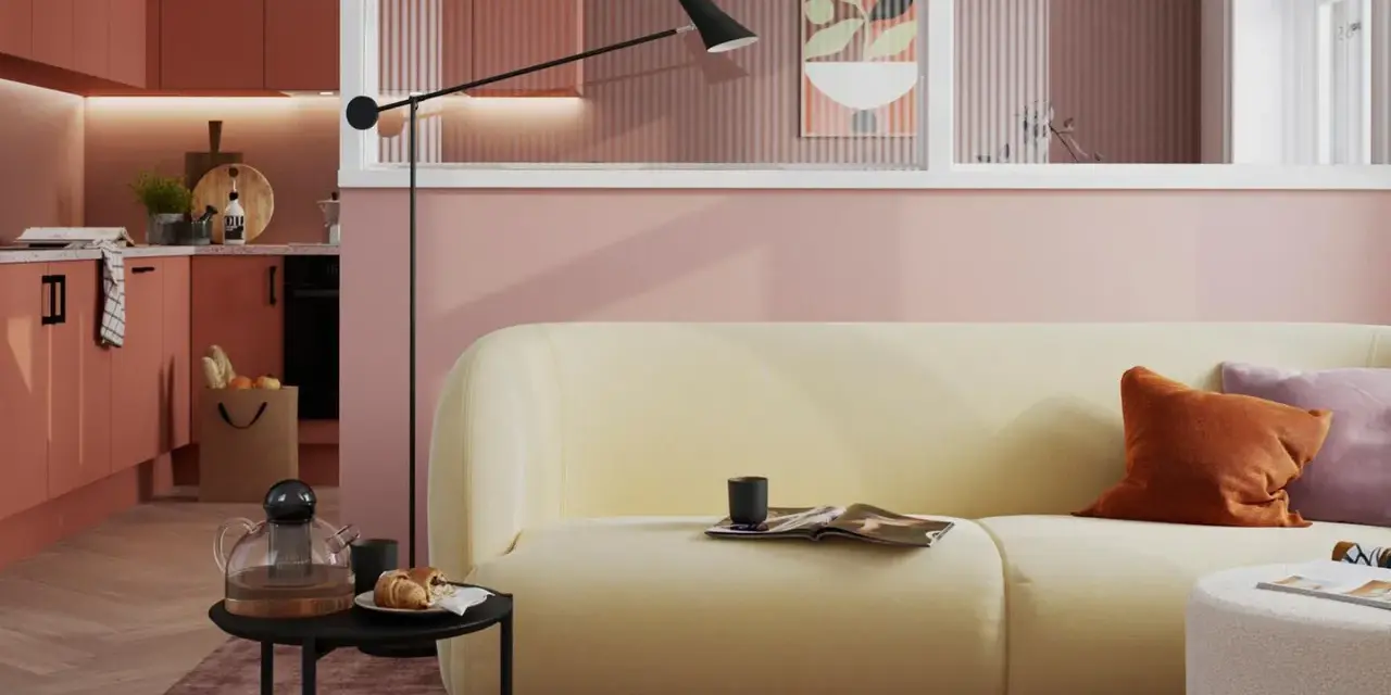 Ein hellgelbes Sofa mit orangefarbenen und lila Kissen vor einer rosafarbenen Wand. Die Frage, welche Farbe passt zu rosa, wird hier stilvoll beantwortet.