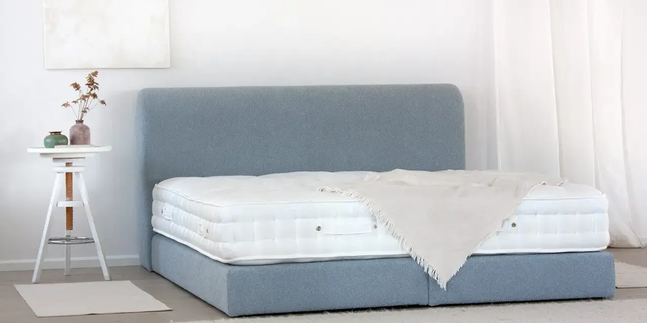 Ein Boxspringbett mit blauem Stoffbezug und weißer Matratze. So wird ein Boxspringbett geliefert: zerlegt und einfach aufzubauen.