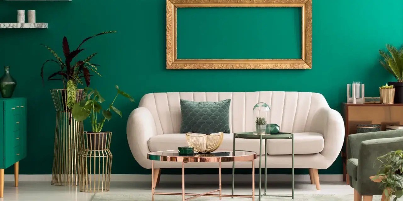 Ein helles Sofa und goldene Akzente harmonieren perfekt mit der petrolfarbenen Wand. Welche Farbe passt zu petrol? Hier sehen wir eine elegante Kombination.