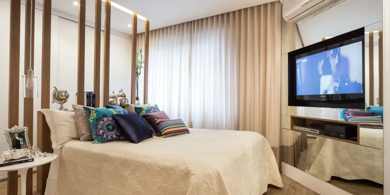 Ein modernes Schlafzimmer mit einem eleganten Bett, vielen Kissen und einem versteckten TV im Spiegel-Schrank.