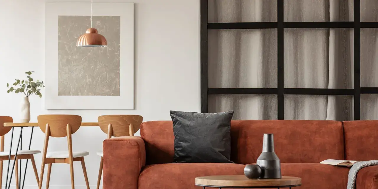 Gemütliches Wohnzimmer mit orangefarbenem Sofa, Holztisch und Stühlen. Tolle inneneinrichtung ideen für ein warmes Ambiente.