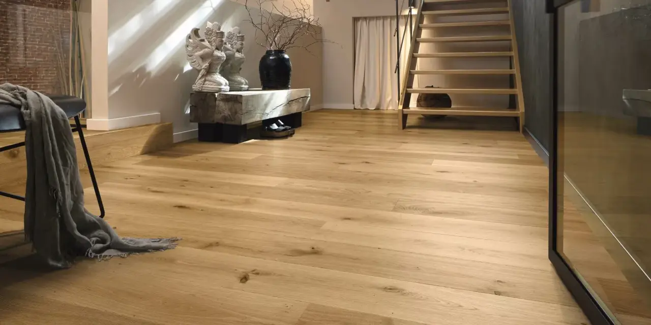 Ein heller Flur mit Treppe und Sitzbank. Der Boden ist aus echtem **Vollholz**, das Wärme und Natürlichkeit ausstrahlt.