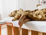 Füße ragen aus einem gemütlichen, braunen Bett hervor. Das Bett ist 210 cm lang und lädt zum Entspannen ein.