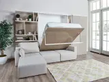 Ein verstecktes Bett im Wohnzimmer wird aus einem Schrank herausgeklappt. Daneben ein Sofa und ein Bücherregal.