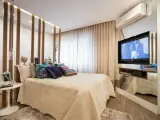 Ein modernes Schlafzimmer mit einem eleganten Bett, vielen Kissen und einem versteckten TV im Spiegel-Schrank.