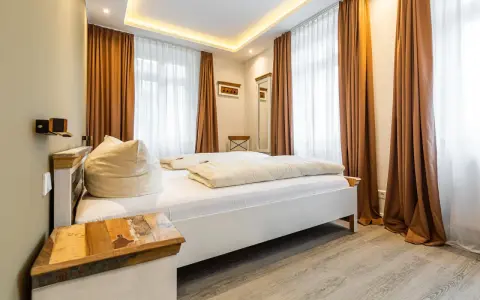 Gemütliches Schlafzimmer mit Doppelbett, Sitzsack und rustikalem Nachttisch. Die Einrichtung der Ferienwohnung ist modern und einladend.