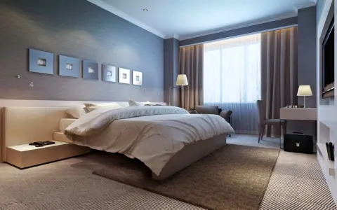 Modernes Schlafzimmer mit einem bequemen Bett, das wie ein wasserbett oder boxspringbett wirkt. Dekorative Wandbilder und ein Schreibtisch mit Lampe.