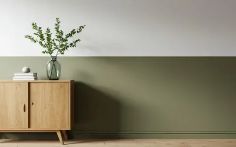 Ein Flur, halbhoch gestrichen in einem beruhigenden Grünton. Ein schlichtes Sideboard aus Holz mit Deko-Elementen.