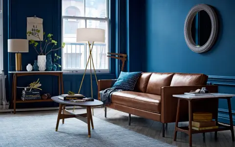 Gemütliches Wohnzimmer mit tiefblauen Wänden, brauner Ledercouch und einem hellblauen Teppich. Die Kombination aus Blau und Braun schafft eine warme Atmosphäre.
