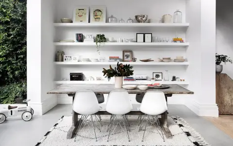 Moderne Esszimmer Wand Ideen: Weiße Regale voller Deko, Geschirr und Bilder über einem rustikalen Holztisch mit weißen Stühlen.